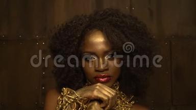 迷人的非洲女人，有着红色的嘴唇，金色的眼影和黑色的卷发，戴着金色的链子